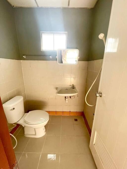 Small bathroom with toilet, sink, shower, and window