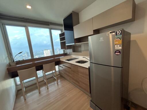 Modern kitchen with large window, light wood flooring, and stainless steel appliances