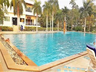 Outdoor pool area with surrounding greenery and adjacent building