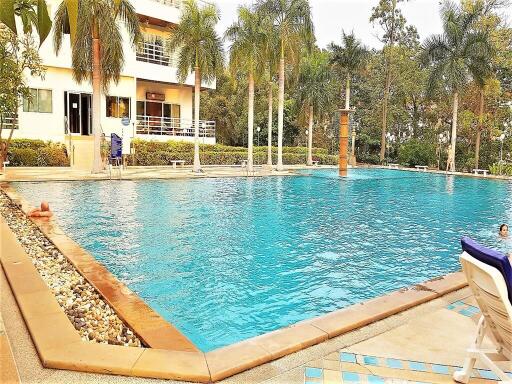 Outdoor pool area with surrounding greenery and adjacent building