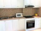 Modern kitchen with white cabinets and mosaic backsplash