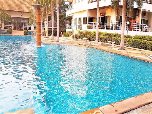 Community swimming pool with fountain and surrounding greenery