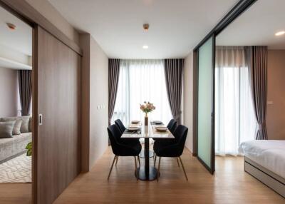 Modern dining area with glass table and black chairs adjacent to living room and bedroom