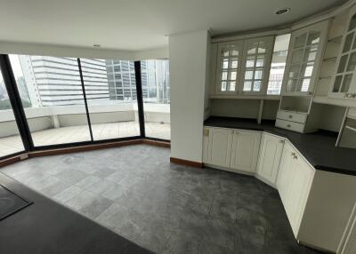 Spacious living area with large windows and kitchen cabinets