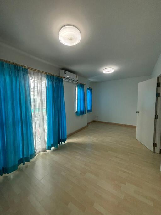 Spacious bedroom with blue curtains and wooden flooring