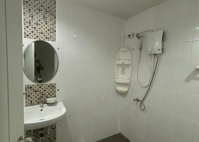 Bathroom with sink, mirror, shower area, and tiled walls