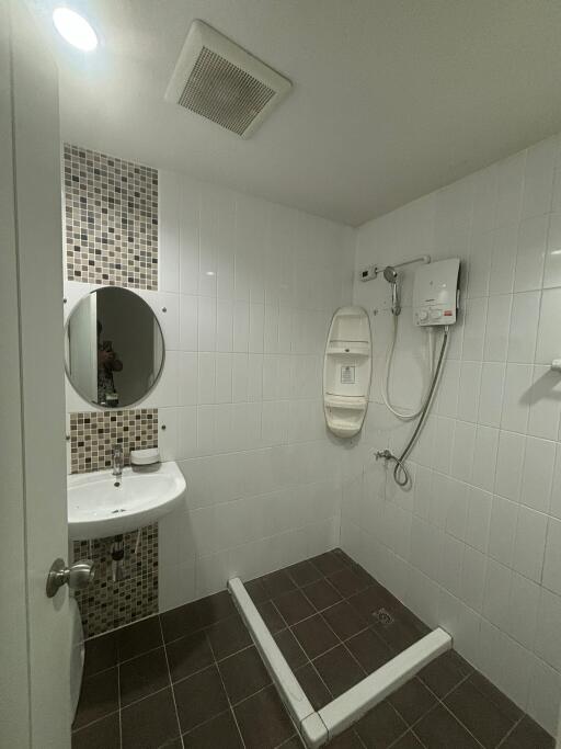 Bathroom with sink, mirror, shower area, and tiled walls