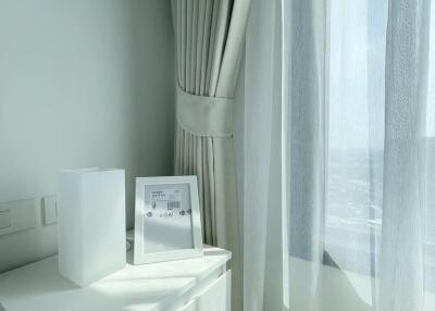 Modern bright bedroom corner with white curtains and a nightstand