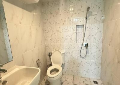 Modern bathroom with white marble tiles, toilet, sink, and shower