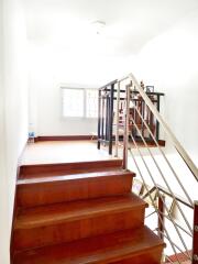 Wooden staircase with metal railing leading to a well-lit room