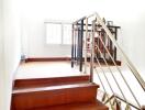 Wooden staircase with metal railing leading to a well-lit room