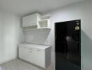 Modern kitchen with black refrigerator and white cabinetry