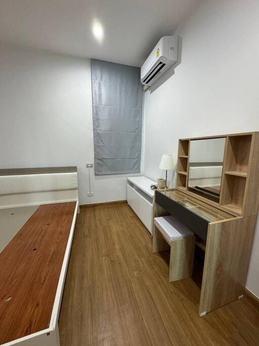 Bedroom with wooden flooring, bed frame, dresser, desk with mirror, and air conditioner