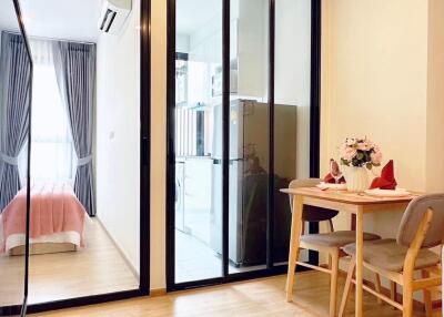 Small dining table and chairs in cozy living space with glass doors leading to bedroom