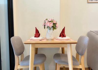 Small dining table setup with two chairs, floral centerpiece, and neatly folded napkins