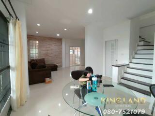 Modern living area with brown sectional sofa, glass table, and staircase