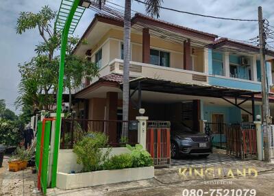 Exterior view of a two-story residential house with a garden and carport