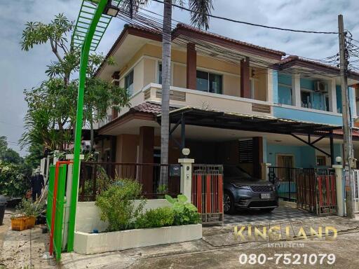 Exterior view of a two-story residential house with a garden and carport