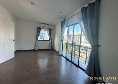 Spacious bedroom with wooden flooring, large window, and balcony access