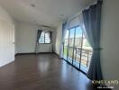 Spacious bedroom with wooden flooring, large window, and balcony access