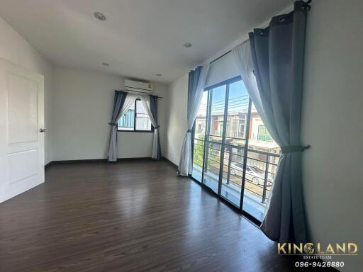 Spacious bedroom with wooden flooring, large window, and balcony access