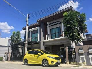 Exterior view of a modern two-story house with a yellow car parked in front