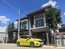 Exterior view of a modern two-story house with a yellow car parked in front