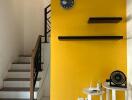 Living room with yellow accent wall and staircase