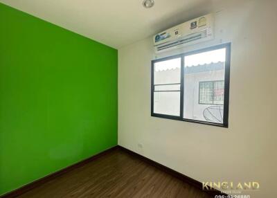 Bedroom with green and white walls, window, air conditioning unit, and wooden flooring