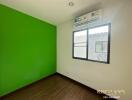 Bedroom with green and white walls, window, air conditioning unit, and wooden flooring