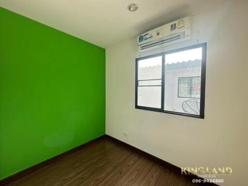 Bedroom with green and white walls, window, air conditioning unit, and wooden flooring