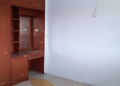 A vacant bedroom with built-in wooden cabinets and a small desk area.