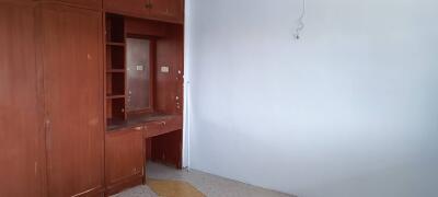 A vacant bedroom with built-in wooden cabinets and a small desk area.