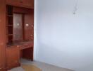 A vacant bedroom with built-in wooden cabinets and a small desk area.