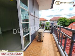 balcony with brown tile flooring, view of rooftops, and air conditioning unit