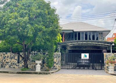 Two-story house with a gated entrance and surrounding greenery