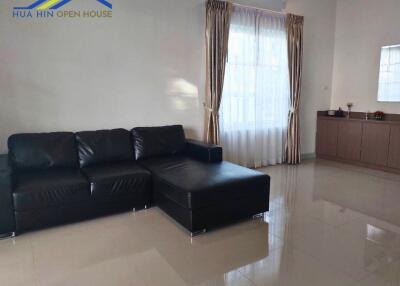 Living room with black leather sectional sofa and large window with curtains