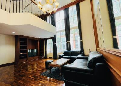 Spacious living room with black leather sofas and large windows