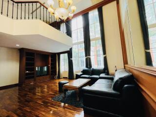 Spacious living room with black leather sofas and large windows