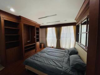 Spacious bedroom with built-in wooden wardrobe and large windows