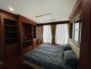 Spacious bedroom with built-in wooden wardrobe and large windows