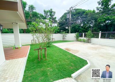 Outdoor garden with green lawn, paved area, and surrounding trees