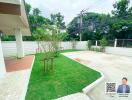 Outdoor garden with green lawn, paved area, and surrounding trees