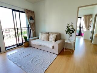 Cozy living room with a sofa, side table, and a large window with curtains