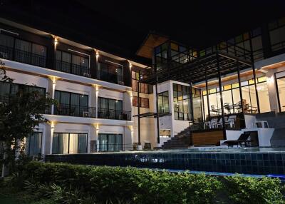 Exterior view of a modern multi-story building with pool at night