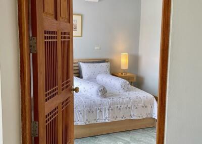 A cozy bedroom with a wooden bed, decorative pillows, and a bedside table with a lamp