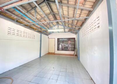 Spacious empty room with tiled flooring, large window, and exposed beams