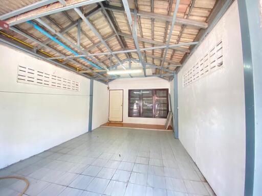 Spacious empty room with tiled flooring, large window, and exposed beams