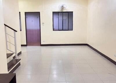 Empty living room with tiled floor and a window with a fan