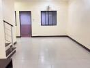 Empty living room with tiled floor and a window with a fan